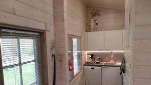 A compact kitchen with white cabinets, a coffee maker, a kettle, and a sink. - Adeli Holiday Cottage Ellivuori with hot tube and grill hut (Ellivuori)
