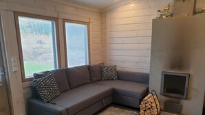 A modern living room with a grey sectional sofa, patterned cushions, a woven rug, and a fireplace. - Adeli Holiday Cottage Ellivuori with hot tube and grill hut (Ellivuori)