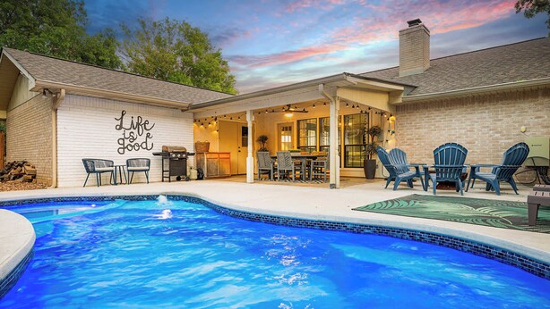Ein Garten mit Pool, Sitzgelegenheit im Freien und einem Schild mit der Aufschrift 'Life is good'.