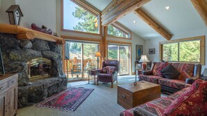 A spacious living room with a stone fireplace, large windows, and a cozy seating area.