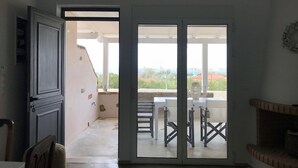 Ein Zimmer mit einer Schiebetür aus Glas, die auf eine Terrasse mit Tisch und Stühlen führt.