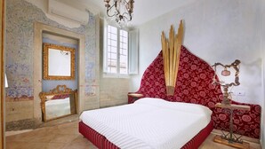 A bedroom with a large bed, a mirror, a chandelier, and patterned wallpaper. - Apartment Leoni Suite in Florence by Mmega (Firenze)