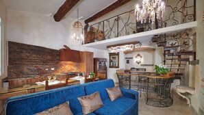 A spacious living area with a blue sofa, wooden cabinets, a chandelier, and a staircase. - Apartment Leoni Suite in Florence by Mmega (Firenze)