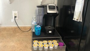 Un comptoir de cuisine avec une machine à café, une bouteille d’eau et un panier de pots de yaourt.