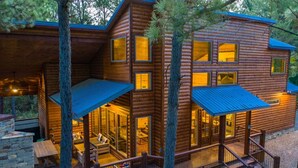 Una baita di legno con più livelli, ampie finestre e una veranda coperta.