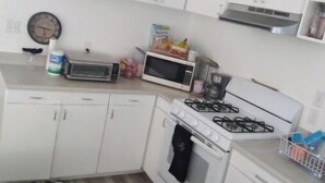 A small kitchen with white cabinets, a microwave, a toaster, and a gas stove. - Hawaiian Princess Paradise (Honolulu)