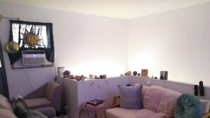 A cozy living room with a sofa, a small table, and a decorative wall piece. - Hawaiian Princess Paradise (Honolulu)