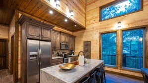 Une cuisine moderne avec des meubles en bois, des appareils en acier inoxydable et un grand îlot central doté de tabourets de bar.