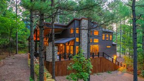 Une cabane à plusieurs étages, dotée d’une façade en pierre, d’une terrasse en bois et d’un escalier menant à l’entrée.