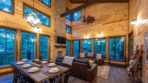 L'intérieur d'un chalet en bois comprend un coin repas, des sièges et de grandes fenêtres.