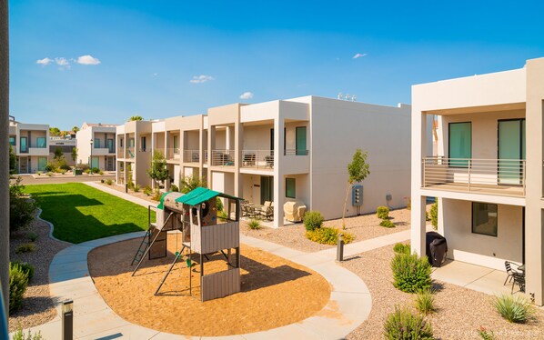 A modern apartment complex with multiple balconies, a playground, and a well-maintained garden. - Abbys Retreat At Green Valley (St. George)