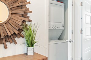 Une salle de bain avec un décor mural en bois, une plante en pot et un lave-linge blanc.