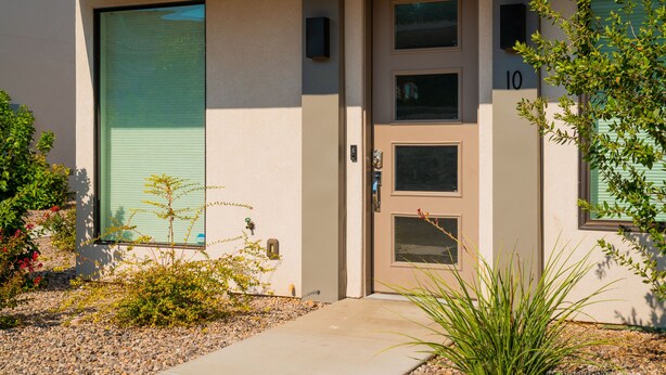 A modern building with a beige facade, a large sliding glass door, and a small entrance door. - Abbys Retreat At Green Valley (St. George)