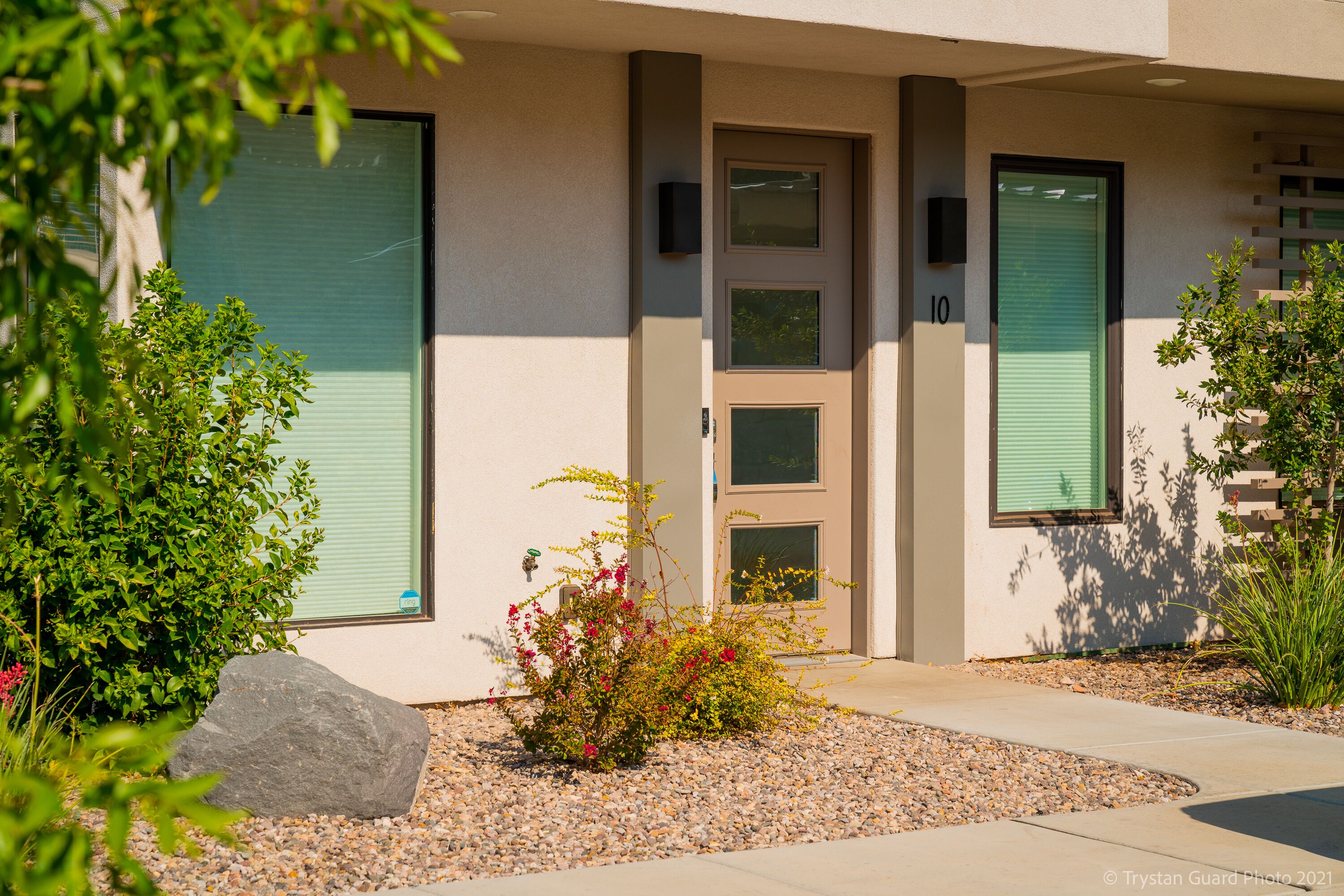 A modern building with a beige facade, a green door, and a number '10' on the wall.