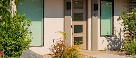 A modern building with a beige facade, a green door, and a number '10' on the wall.
