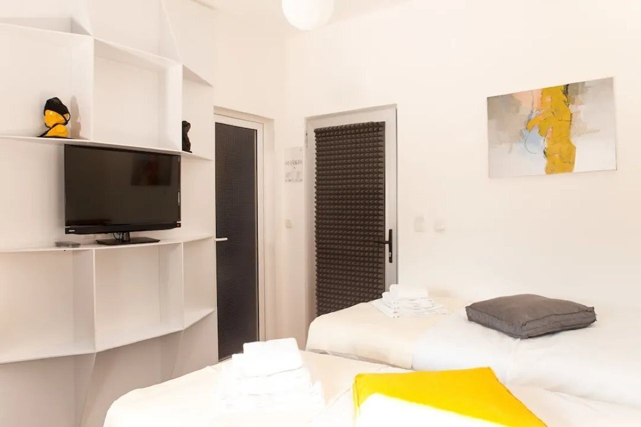 Ein Hotelzimmer mit Bett, Fernseher auf einem Tisch, einer Tür mit schalldämmender Platte und einem Bild an der Wand.