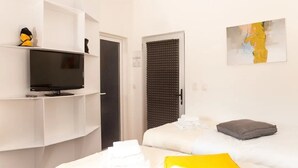 A hotel room with a bed, a television on a stand, a door with a soundproof panel, and a painting on the wall. - Concept Hotel Central (Skopje)
