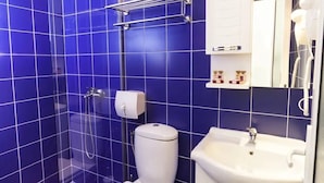 A bathroom with blue tiles, a toilet, a sink, and a shower. - Concept Hotel Central (Skopje)