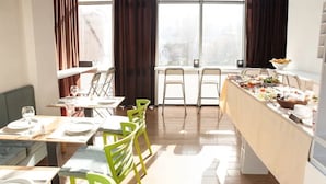 A dining area with a buffet setup, multiple tables, and chairs. - Concept Hotel Central (Skopje)