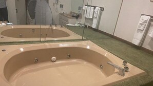A bathroom with a large beige bathtub, a mirror, and a sink. - Condos.  hot tub, deck,  Patoka lake (8800 acres) boating and beach, concessions   (French Lick)