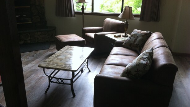 A living room with a brown leather sofa, a patterned coffee table, and a lamp on a side table. - Condos.  hot tub, deck,  Patoka lake (8800 acres) boating and beach, concessions   (French Lick)