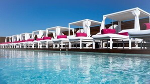 Ein Poolbereich mit mehreren weißen Liegestühlen, jeweils mit einer rosafarbenen Auflage.