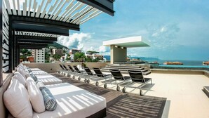 A rooftop lounge with sun loungers and a view of the sea.