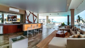 A spacious living area with a bar, seating, and a view of the ocean.
