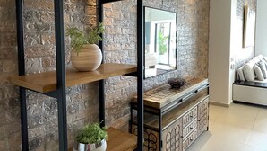 A modern living room with exposed brick walls, wooden shelves, and a console table with decorative items.