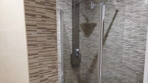 Een moderne badkamer met een glazen douchecabine, een toilet en een wastafel.