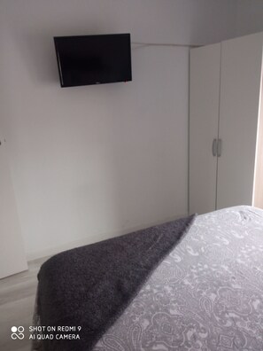 A bedroom with a bed, a wardrobe, and a mounted TV. - A SMALL Home (Alcalá de Henares)