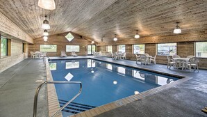 An indoor swimming pool with wooden walls and ceiling, surrounded by white chairs and tables. - Gull Lake Resort Escape: Pool and ORV Trails (Nisswa)