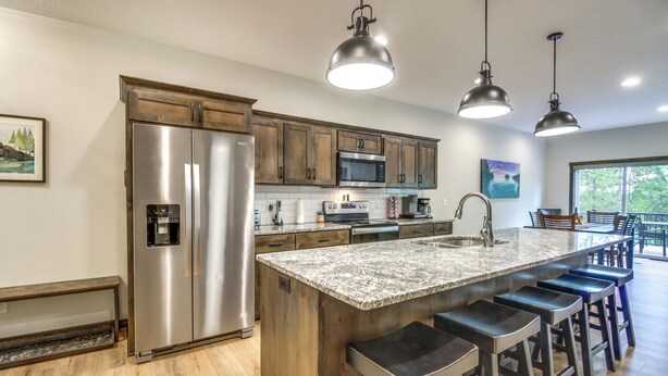 A modern kitchen with stainless steel appliances, a granite countertop, and bar stools. - Gull Lake Resort Escape: Pool and ORV Trails (Nisswa)