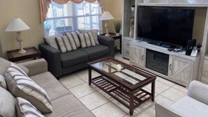 Un salon comprenant un canapé, une table basse, un téléviseur et un meuble.