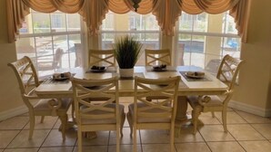 Un coin repas avec une table ronde, six chaises et un lustre.