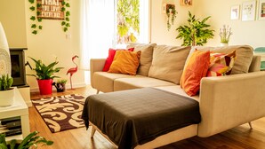 A living room with a beige sofa, a brown rug, and various potted plants. - Peace & Love Flat Nazaré - Peace & Love (Nazaré)
