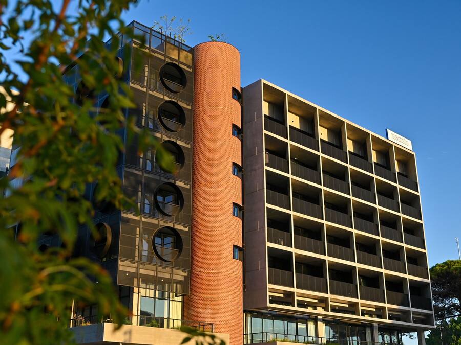 Un edificio moderno con una torre cilíndrica de ladrillo y varios pisos con balcones.
