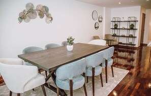 A dining area with a wooden table, light blue upholstered chairs, and a white vase with a plant.