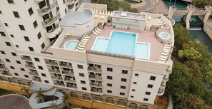 A high-rise hotel with multiple balconies, a rooftop pool, and a surrounding landscaped area. - Savor the City Attractions & Resort-Style Fun in San Antonio, TX (San Antonio)
