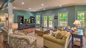 A spacious living room with a sofa, armchairs, a coffee table, and a bookshelf. - Luxe Lake Cumberland Retreat w/ Decks on 1 Acre! (Jamestown)