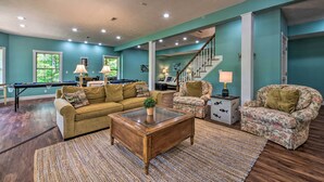 A spacious living room with a pool table, a sofa, and a chair. There is a staircase leading to another level. - Luxe Lake Cumberland Retreat w/ Decks on 1 Acre! (Jamestown)