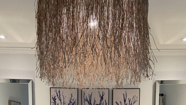 Une chambre à coucher avec un grand lit, deux tables de chevet avec des lampes et trois œuvres d’art encadrées accrochées au mur au-dessus du lit.