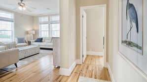 A spacious living room with a ceiling fan, a white sofa, a coffee table, and a large window. - *NEW* - LOCATION, LOCATION - 250 Feet to the Beach - Sleeps 6 (Bay St Louis)