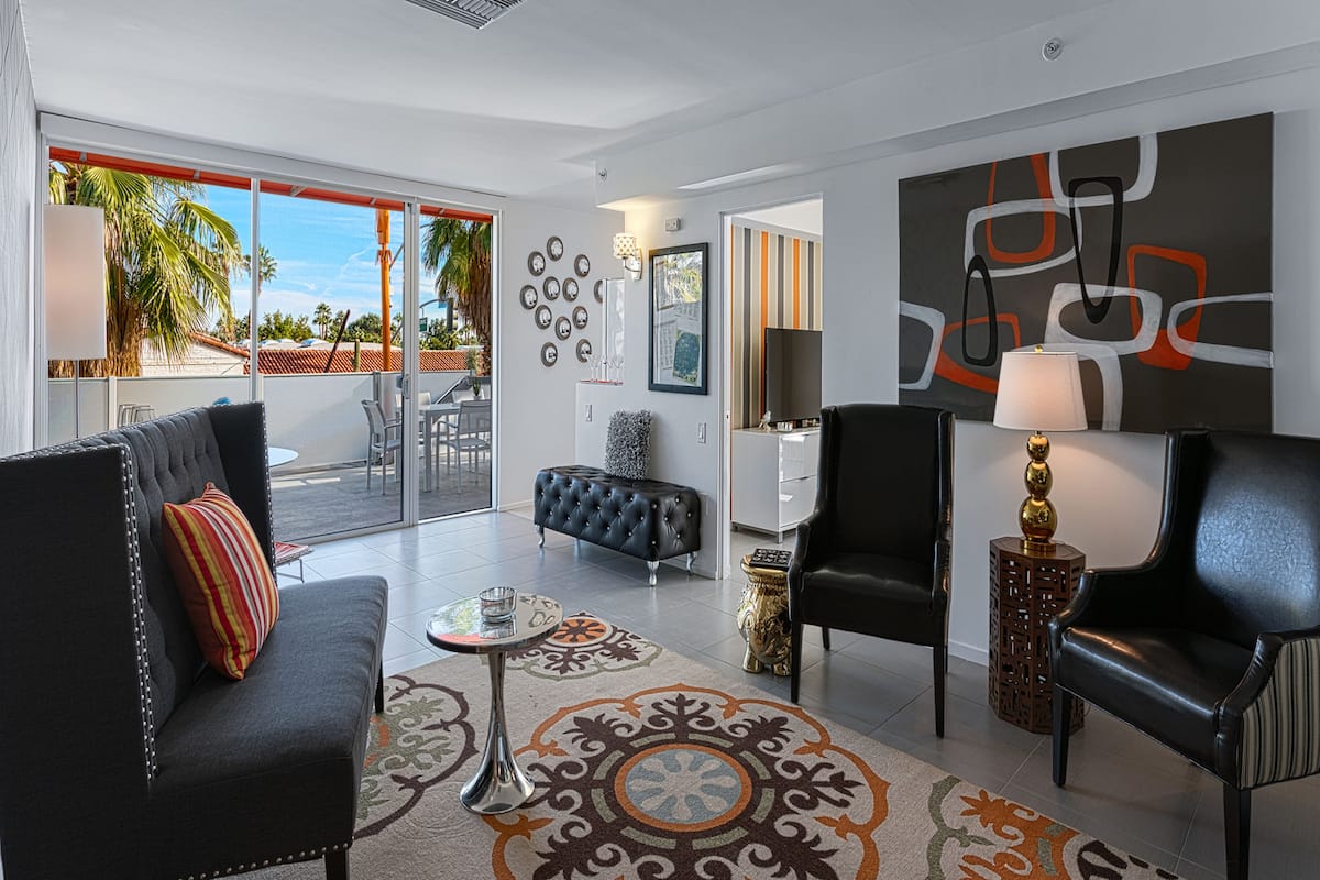 A modern living room with a sofa, chairs, a coffee table, and a patterned rug.