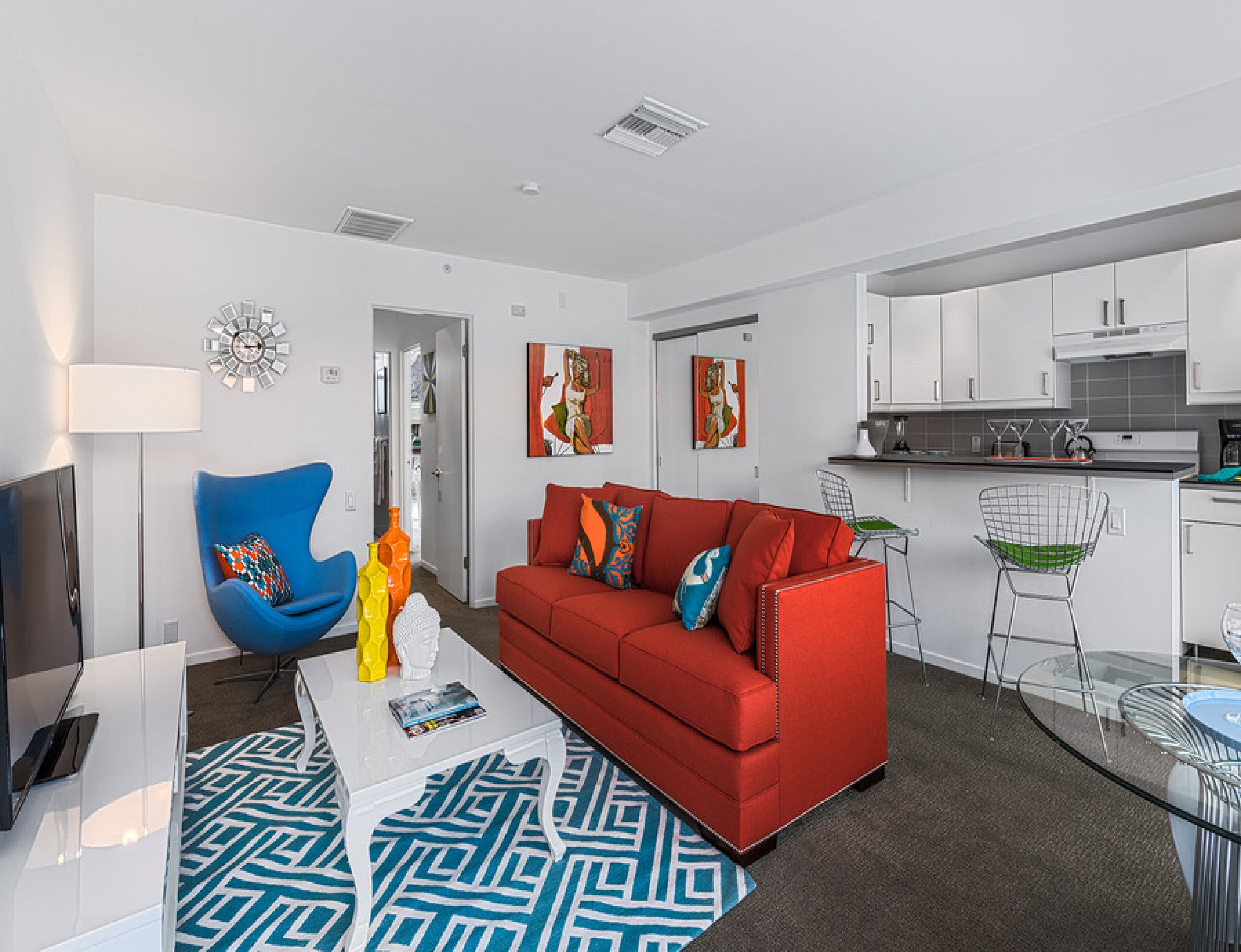 Un salon moderne avec un canapé rouge, un fauteuil bleu et une table basse blanche.