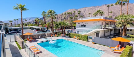 A pool area with lounge chairs, a swan float, and a building labeled "The Twist" in the background.