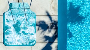 A pool with clear blue water and a poolside area with a blue inflatable lounge chair and metal pool ladder.