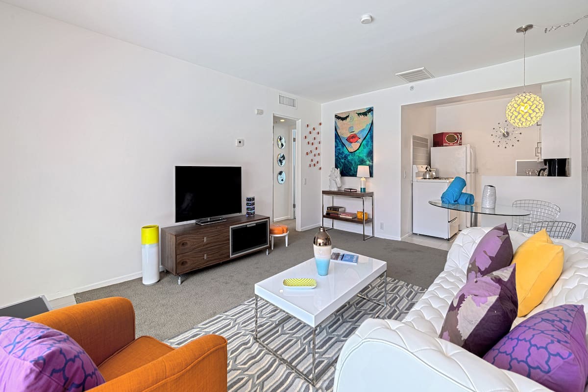 A modern living room with a flat-screen TV, a coffee table, and a sofa with patterned cushions.