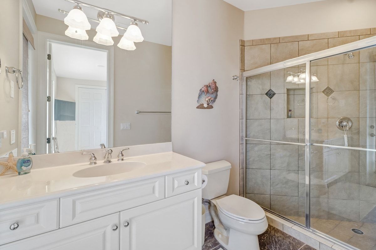 A bathroom with a white vanity, a toilet, and a glass-enclosed shower.