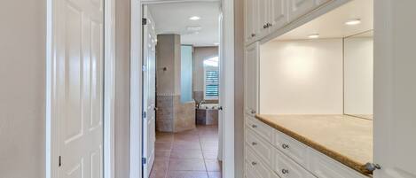 A hallway with white cabinetry and a large mirror.
